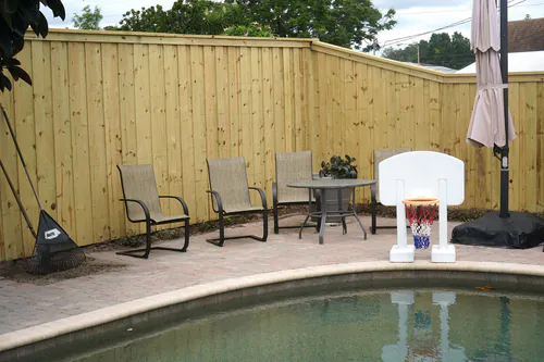 Board on board wood privacy fence with a cap rail enclosing an Orlando pool patio with paver decking and patio furniture