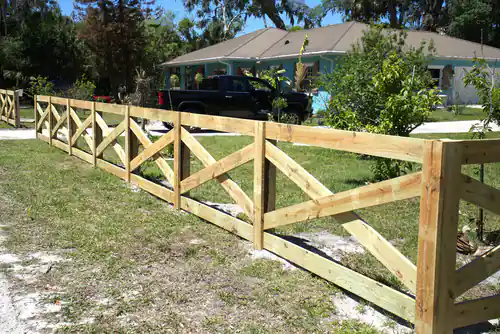 Crossbuck wood fence running along the front property line of a New Smyrna Beach home with a pickup truck parked behind it