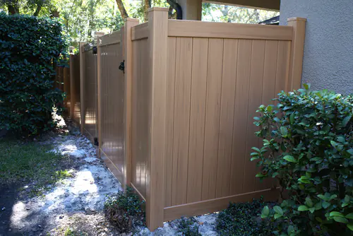Cypress colored vinyl privacy gate and fence section fitted between a stucco house wall and a hedge in Lake Mary
