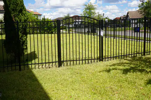 Black aluminum fence with an arched top gate opening onto a lawn in a DeBary neighborhood
