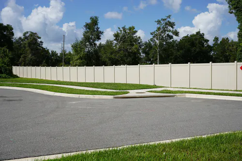 Tan vinyl privacy fence running straight behind the curving sidewalk at the end of an Apopka road with the pavement in the foreground