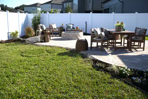 White vinyl privacy fence enclosing a Deltona backyard with a paver patio, stone fire pit and outdoor dining set